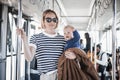 Mother carries her child while standing and holding on to bar holder on bus. Mom holding infant baby boy in her arms Royalty Free Stock Photo