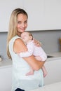 Mother carrying her baby in kitchen at home Royalty Free Stock Photo