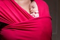 Mother carrying her cute baby daughter in sling. Newborn baby sleeping in a sling, in the embrace of her mother. The baby girl is Royalty Free Stock Photo