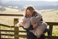 Mother carrying her daughter by a gate in the countryside Royalty Free Stock Photo