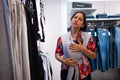 A mother carrying a newborn child in babywearing fashion is seen shopping inside an apparel and clothing shop in the city downtown