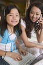 Mother on cell phone watching daughter using laptop in living room portrait Royalty Free Stock Photo