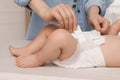 Mother changing baby`s diaper on bed at home, closeup Royalty Free Stock Photo