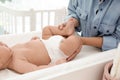 Mother changing her baby`s diaper on table at home, closeup Royalty Free Stock Photo