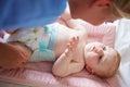 Mother Changing Baby Son's Nappy As He Lies On Mat