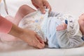 Mother changing diaper of adorable baby with a hygiene set for babies on the background Royalty Free Stock Photo