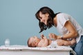 Mother changing diaper on her baby on table over blue background
