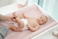 Mother changing her baby`s diaper on table at home Royalty Free Stock Photo