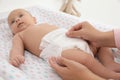 Mother changing her baby`s diaper on table at home Royalty Free Stock Photo