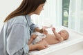 Mother changing her baby`s diaper on table at home Royalty Free Stock Photo