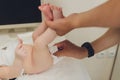 Mother changing a tiny newborn baby`s nappy as it lies on its back on a changing table in the nursery. baby hygiene a Royalty Free Stock Photo