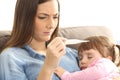 Mother checking thermometer with her ill baby