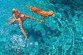 Mother with child on back swim with dog in pool