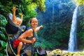 Mother with child in backpack hiking to jungle waterfall Royalty Free Stock Photo