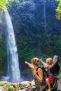 Mother with child in backpack looking at jungle waterfall Royalty Free Stock Photo