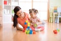 Mother and child building from toy blocks at home. Family concept.