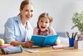 Mother and child daughter doing homework writing and reading at Royalty Free Stock Photo