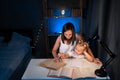 Mother and child daughter doing homework writing and reading at home at night, above view. child, preschooler and