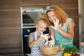 Mother and child daughter girl having fun while making dinner at the kitchen. Royalty Free Stock Photo