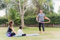 mother and child daughter practicing doing yoga exercises outdoors cheer father playing with hula