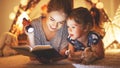 Mother and child daughter reading a book and a flashlight before Royalty Free Stock Photo