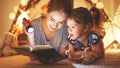 Mother and child daughter reading a book and a flashlight before