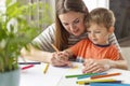 Mother and child drawing with pencils sitting at the desk at home Royalty Free Stock Photo