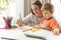 Mother and child drawing with pencils sitting at the desk at home Royalty Free Stock Photo