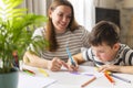 Mother and child drawing with pencils sitting at the desk at home Royalty Free Stock Photo