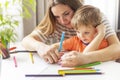 Mother and child drawing with pencils sitting at the desk at home Royalty Free Stock Photo