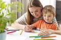 Mother and child drawing with pencils sitting at the desk at home Royalty Free Stock Photo