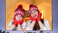 Mother and child girl look out the window as the snow falls. Royalty Free Stock Photo