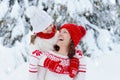 Mother and child in knitted winter hats play in snow on family Christmas vacation. Handmade wool hat and scarf for mom and kid.