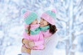 Mother and child in knitted winter hats play in snow on family Christmas vacation. Handmade wool hat and scarf for mom and kid.