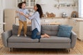 Mother and child laughing having fun, holding hands and jumping on sofa at home. Happy family. Royalty Free Stock Photo