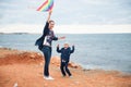 Mother and child playing with a kite against the background of the sea in cloudy weather Royalty Free Stock Photo