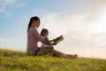 Mother and daughter spending time together reading a book, while sitting at the park Royalty Free Stock Photo