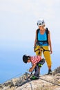 Mother, child in safety equipment climb by via ferrata route