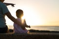 Mother and child sitting together on the beach, watching the beautiful sunset.