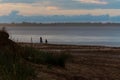 Mother and child at sunset walking on the sand by the sea Royalty Free Stock Photo