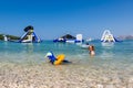 Mother and child swim and having fun in the water with inflatable slides in the background. Royalty Free Stock Photo