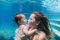 Mother with child swimming underwater in blue beach pool Royalty Free Stock Photo