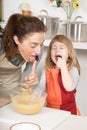 Mother and child tasting whipped cream at the same time