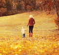 Mother and child walking together in autumn park with yellow leaves Royalty Free Stock Photo