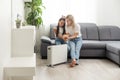 Mother and child warming hands near electric heater at home