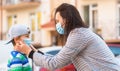 Mother, child wear facemask during coronavirus, flu outbreak. Mom puts a medical mask on her son. Child and mom in