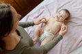 Mother and child on a white bed. Baby girl in diaper. Mom playing with her baby Royalty Free Stock Photo