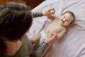 Mother and child on a white bed. Baby girl in diaper. Mom playing with her baby Royalty Free Stock Photo