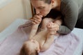 Mother and child on a white bed. Baby girl in diaper. Mom playing with her baby Royalty Free Stock Photo