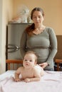 Mother and child on a white bed. Baby girl in diaper. Mom playing with her baby Royalty Free Stock Photo